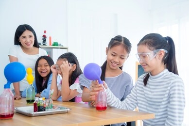 group of young asian schoolgirls doing experiment in chemistry classroom.
