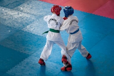 taekwondo.  kids in traditional kimano, hard hats and gloves. sports duel. text on jacket: taekwondo is the name for martial art.
