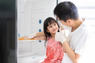 asian daughter is helping father to clean the refrigerator with fully happiness moment, concept of kid executive function development by housework responsibility and happy time in family lifestyle.
