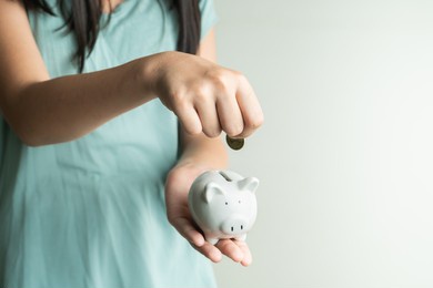 saving and business concept, cute girl with piggy bank and coins at home