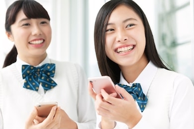 female student in uniform with smartphone
