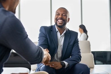 two happy mature business men shaking hands in office. successful african american businessman in formal clothing closing deal with handshake. multiethnic businessmen shaking hands during a meeting.