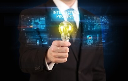businessman holding lightbulb with intellectual property inscription, online security idea concept