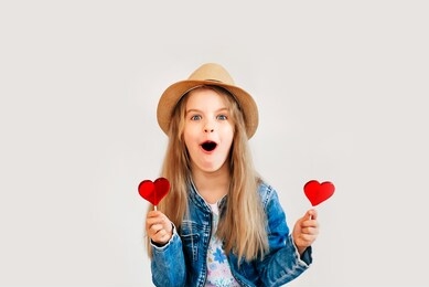 portrait of a beautiful stylish fashionable girl in glasses, with a heart-shaped lollipop, on a white background, free time summer vacation. close up, selective focus