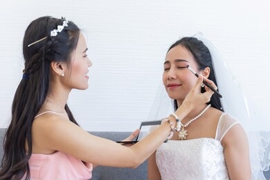 a woman makeup artist is making up an asian bride for her wedding.