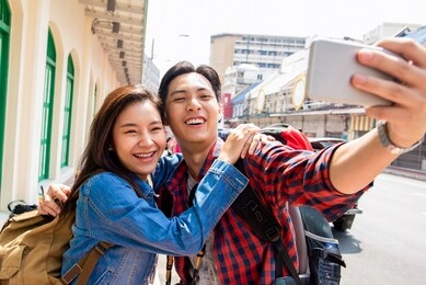 young asian tourist girl taking selfie with boyfriend during summer vacations in bangkok city thailand