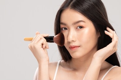 beautiful asian young woman smile and holding make up brush with healthy clean and fresh skin feeling so happiness and cheerful,isolated on white background,beauty cosmetics concept