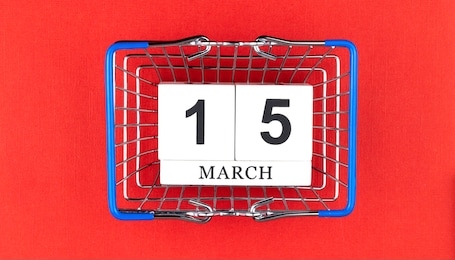 perpetual wooden calendar and the consumer basket. march, 15: world consumer rights day. top view, beautiful red background. 