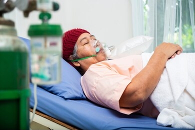 asian elderly woman wearing wool hat with oxygen mask to breathing while  lying on patient bed, senior female medical and healthcare concept