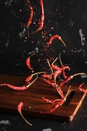 falling dried red hot chili with sichuan pepper seasoning mala powder on wood board isolated background