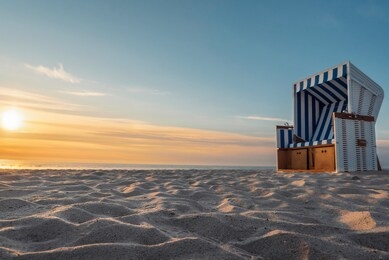 beach landscape at sunset. north sea beach chair on white sand near seawater on sylt island, germany.