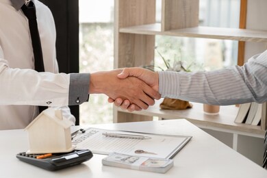 businessmen and brokers real estate agents catch hand after completing negotiations to buy houses insurance and sign contracts. home insurance concept.