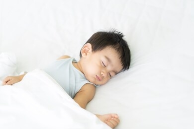 a cute little asian baby boy is peaceful sleeping on the bed in the bedroom with happiness moment, concept of first year growth and development of the child.