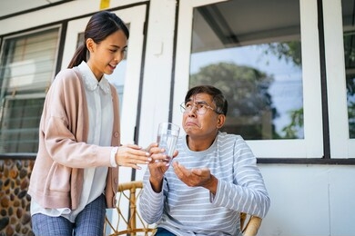 ponytail woman give her old father the medicine for his disease but her father does not want to take it.