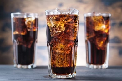 three cola glass with ice cubes and bubbles. cold sweet drink on wooden background