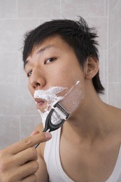 portrait of mid adult asian man shaving in bathroom