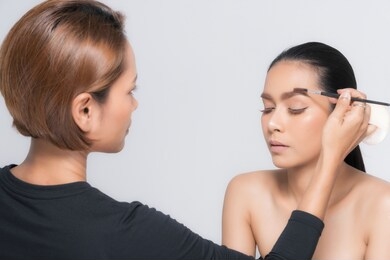 young beautiful asian woman applying makeup by makeup artist on location.