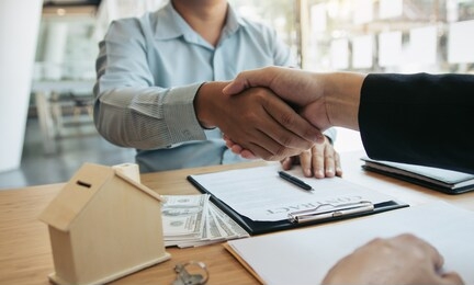 home sales agents and buyers work on signing new homes and shaking hands.