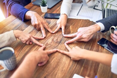 group of business workers standing with hands together. doing symbol with fingers at the office