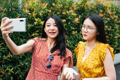 two asian beautiful women selfie with smartphone. vlogging or recording video. cheerful pretty female women vlogging while traveling in thailand.