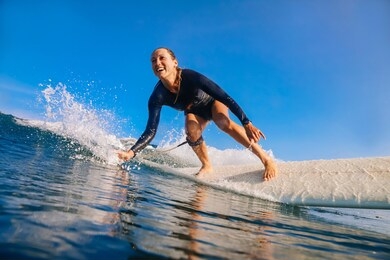 female surfer on a blue wave at sunny day