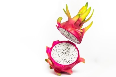 isolated dragon fruit is pitaya or pitahaya on white background. action image, dragon fruit is cut in half, one half on ground, the other half is float in air. sharp cut on fruit by knife.