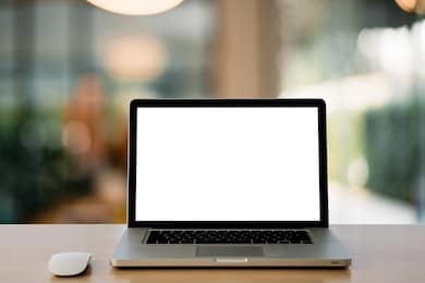 empty space,wooden computer desk and laptop with blank screen and wireless mouse in office with modern blurred background light bokeh.- image