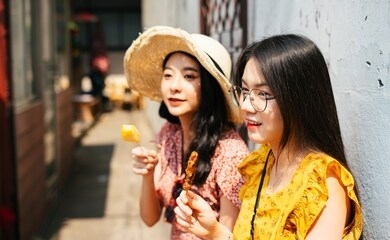 two young beautiful thai asian traveler women bestfriend enjoy eating street food in thailand together.