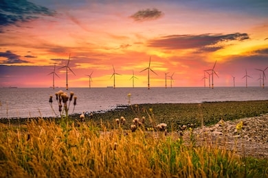 offshore wind turbine in a wind farm under construction off the england coast at sunset