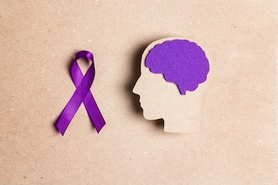 purple awareness ribbon and brain symbol on a brown background. epilepsy disease or alzheimer disease awareness world day.