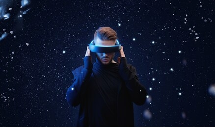 young man in hoodie on virtual reality background. guy using vr helmet. augmented reality, future technology, game concept. blue neon light. 