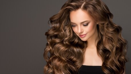 beautiful model girl with long wavy and shiny hair . brunette woman with curly hairstyle