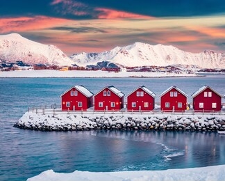 traditional red wooden houses on the shore of offersoystraumen fjord. fantastic winter sunset on vestvagoy island. picturesque evening view of lofoten islands, norway, europe.  life over polar circle.