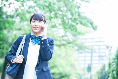 a female student in a uniform making a phone call