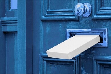 sending a gift in the post.postal white box the parcel is delivered through the parcel door opening.white post box and old aged grunge blue wooden door.
