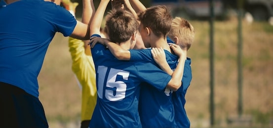 kids sport team gathering and rising hands. children play sports. boys in sportswear jersey uniforms having shout team. youth sports for children. youth football academy background with copy space 