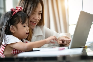 mother's day.little girl looking at laptop computer with her mom.concept family happy. stay home