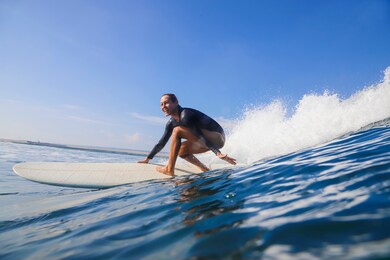 female surfer on a blue wave at sunny day