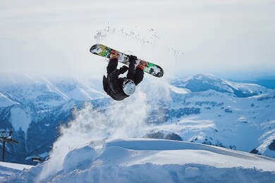 
snowboarder jumps and does a trick in the mountains