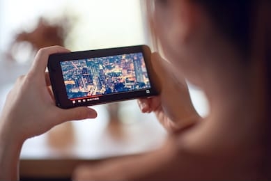 online movie stream with smartphone. woman watching film on mobile phone with imaginary video player service.