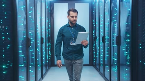 caucasian it engineer activating digital database server room with tablet. bearded specialist inspecting rack internet servers at data center computer security. zoom out.