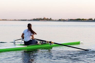 the girl is engaged in rowing sitting in a boat rowing oars in rafting on the river