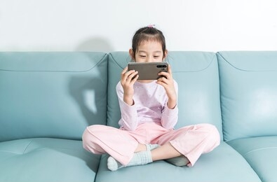 asian child little girl playing game or watching video on mobile phone. 