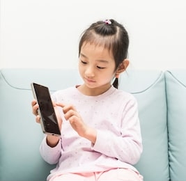 asian child little girl playing game or watching video on mobile phone. 