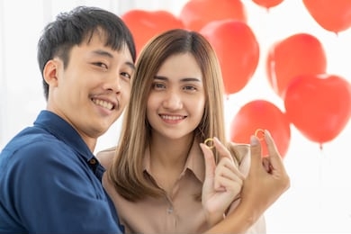 cute young and pretty asian woman and man compare the set of two golden rings with smile and happy moments of lovers. concept for young couple plan for sharing time and wedding ceremony in the future.