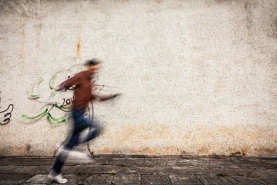 man run through in front of a brick wall