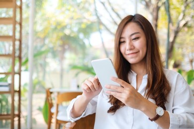 closeup image of a beautiful asian woman holding and using mobile phone 