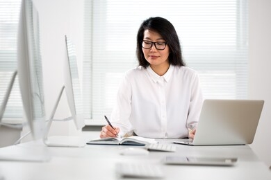 asian business woman smiling at camera at workplace in an office