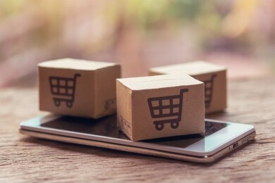 online shopping - paper cartons or parcel with a shopping cart logo and smartphone on wood table top. shopping service on the online web and offers home delivery.