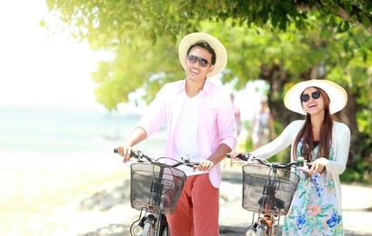portrait of happy asian young couple with bicycle on the beach having fun together